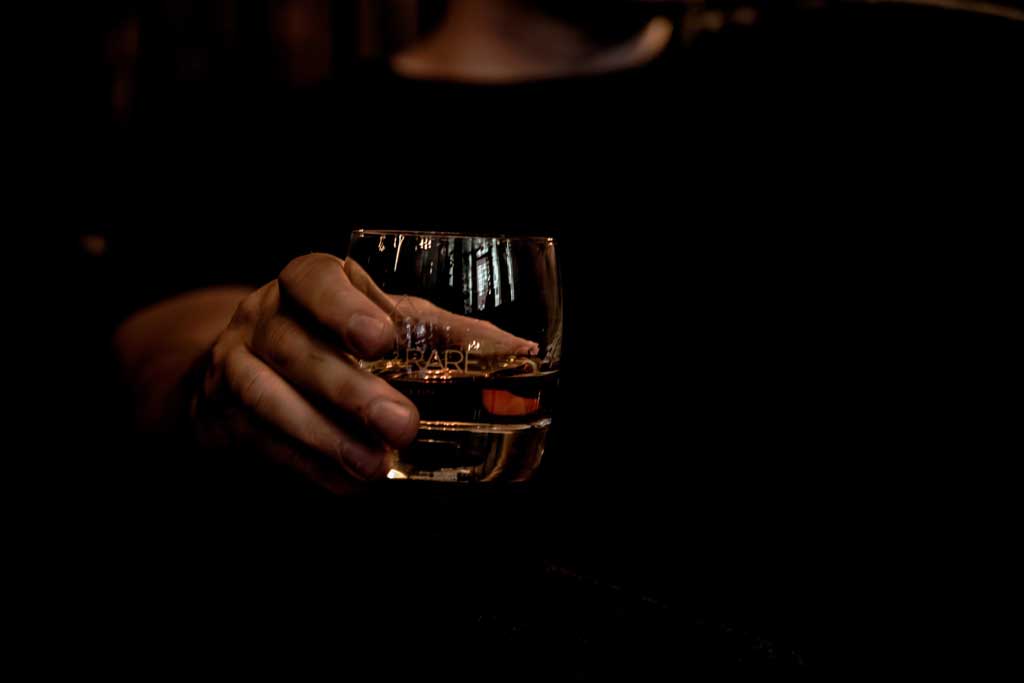 Person holding a whisky glass in dark room