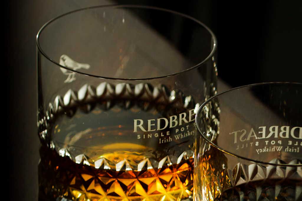 Two Redbreast whiskey drinking glasses beside each other on dark table