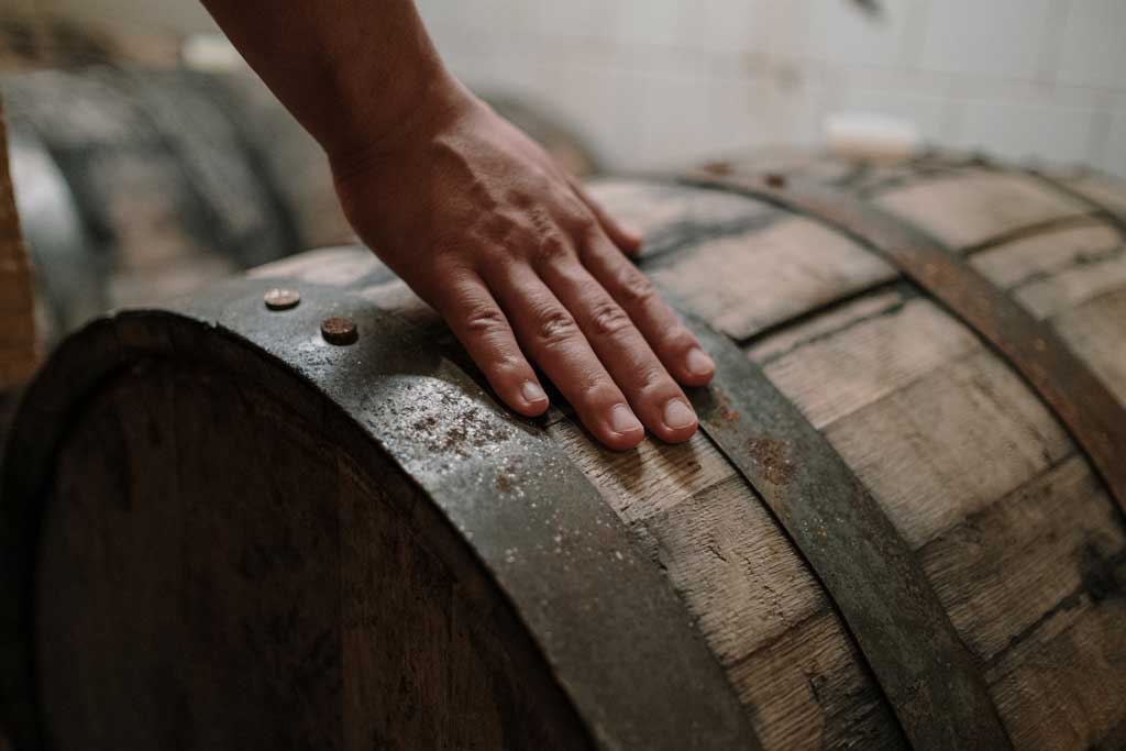 Close view of person touching whiskey barrel