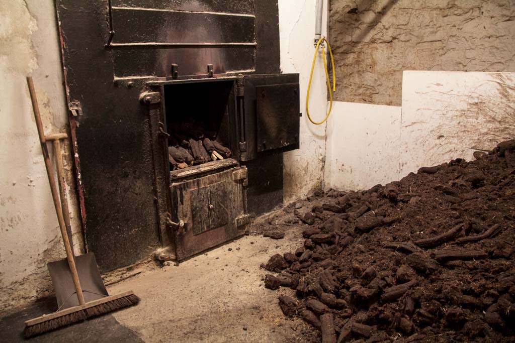 Peat stacked beside kiln used to dry malted barley to make whisky
