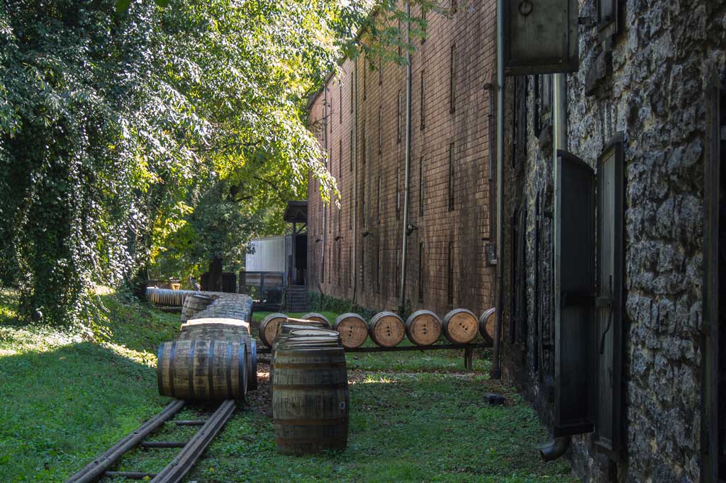Oak barrels outside Woodford Reserve whiskey distillery building on bright summer day