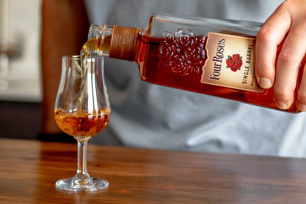 Person pouring Four Roses Single Barrel Bourbon into drinking glass