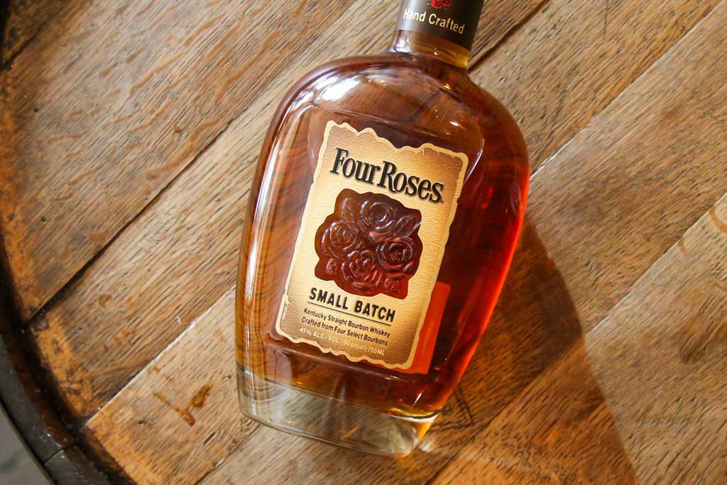 Aerial view of Four Roses Small Batch bourbon bottle on top of whiskey barrel