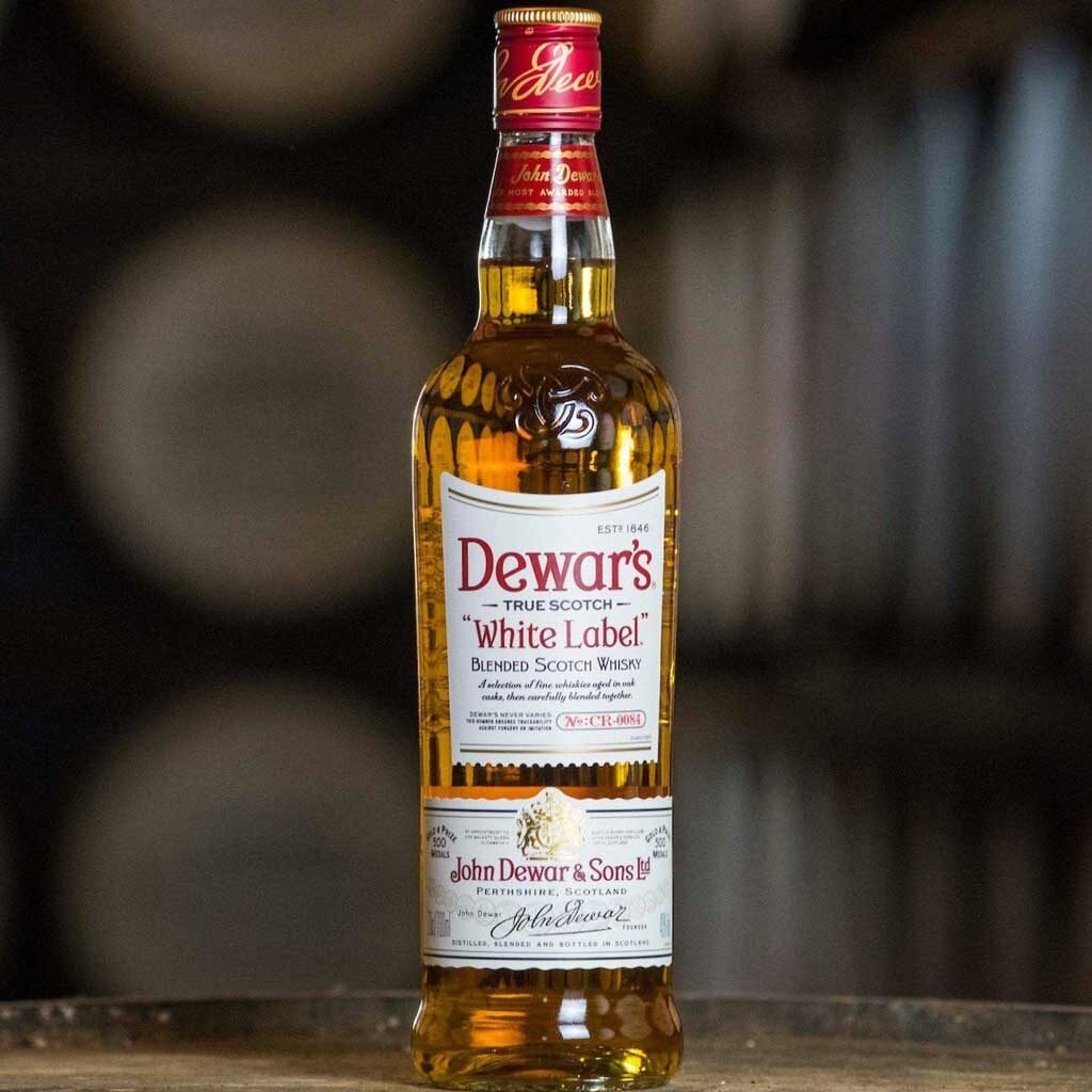 Bottle of Dewar's White Label blended Scotch whisky on top of cask