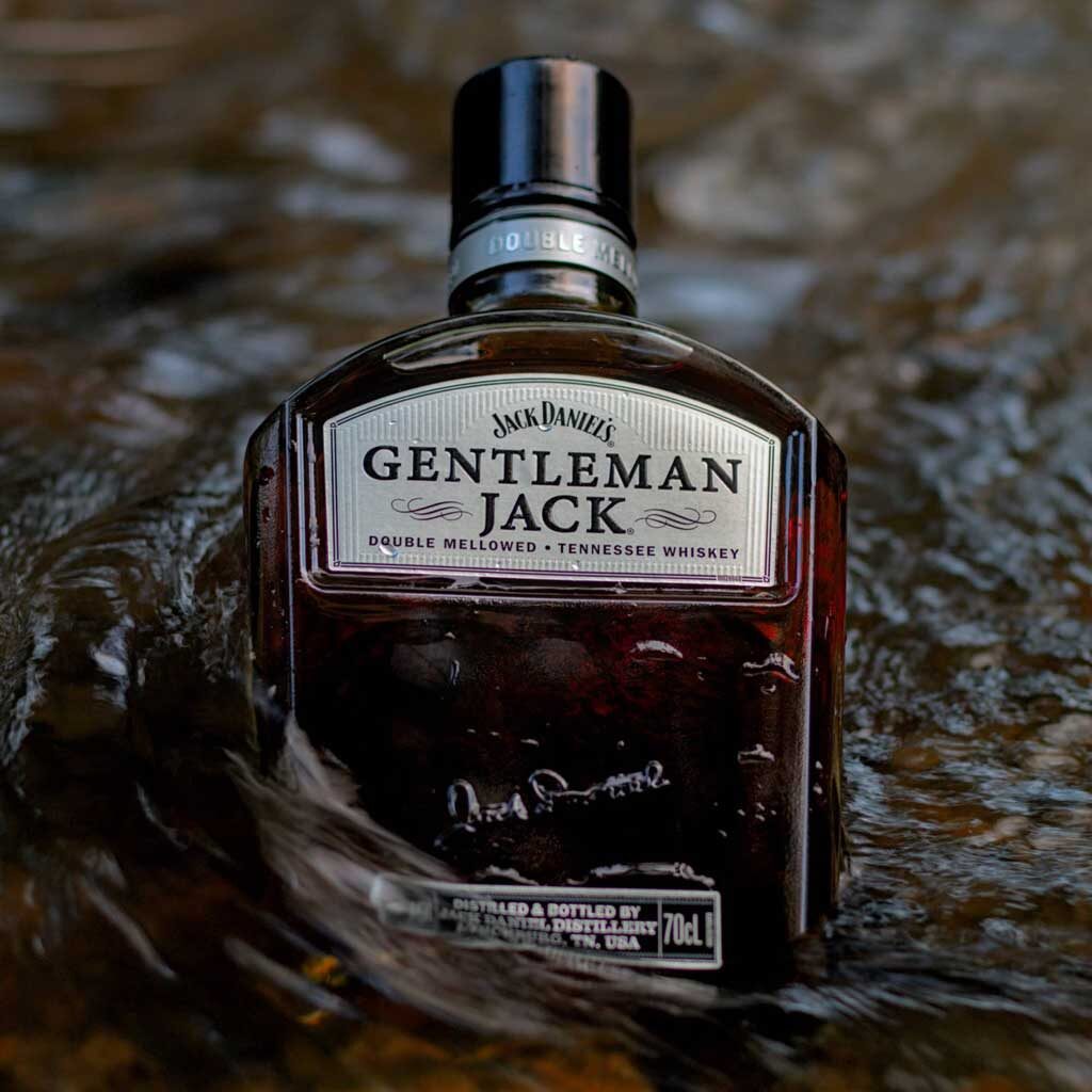 Bottle of Gentleman Jack Tennessee whiskey in flowing water