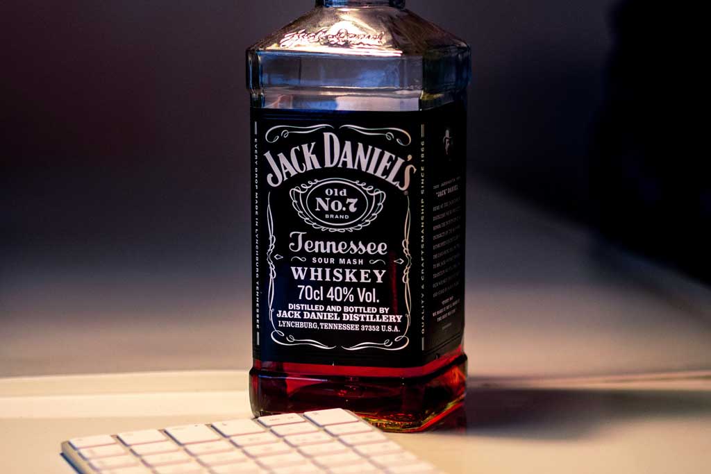 Bottle of Jack Daniels Tennessee Whiskey beside computer keyboard