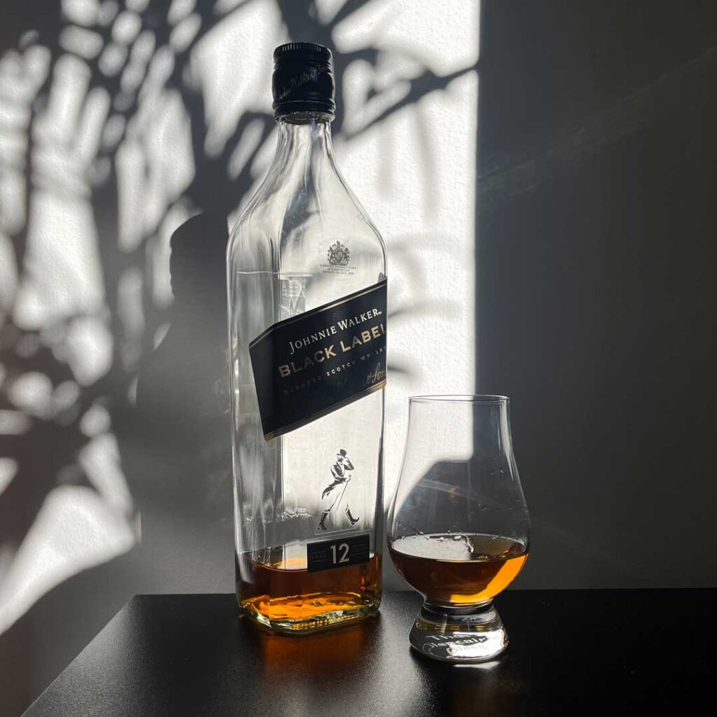 Bottle of Johnnie Walker Black Label whisky beside Glencairn drinking glass