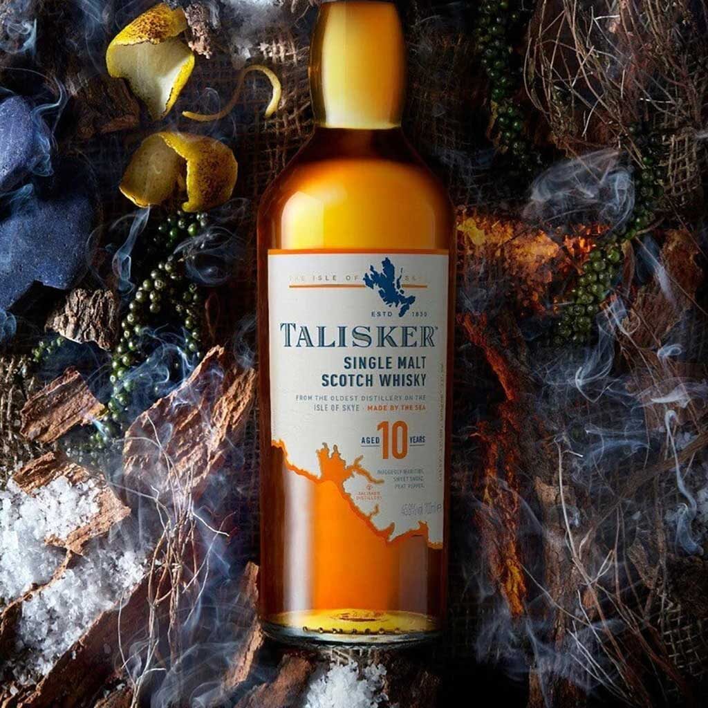 Bottle of Talisker 10 whisky lying amongst colourful seaweed and smoke
