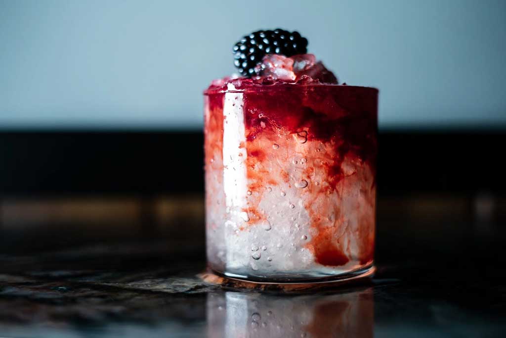 Close view of a Dramble whisky cocktail in a rocks drinking glass topped with berries