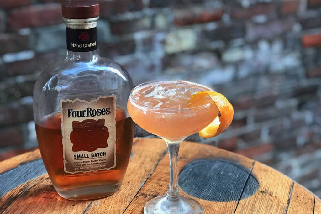 Cocktail drink beside bottle of Four Roses bourbon whiskey