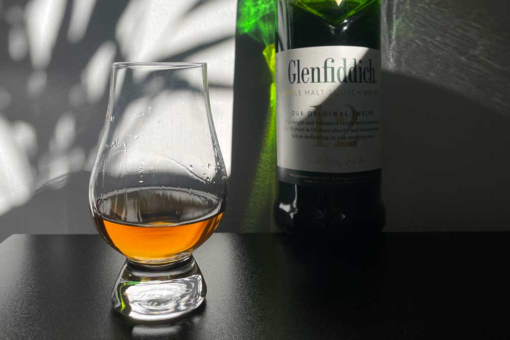 Glencairn drinking glass beside Glenfiddich 12 whisky bottle