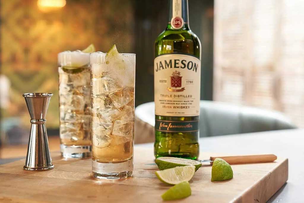 Two highball cocktails beside Jameson whiskey bottle on kitchen chopping board
