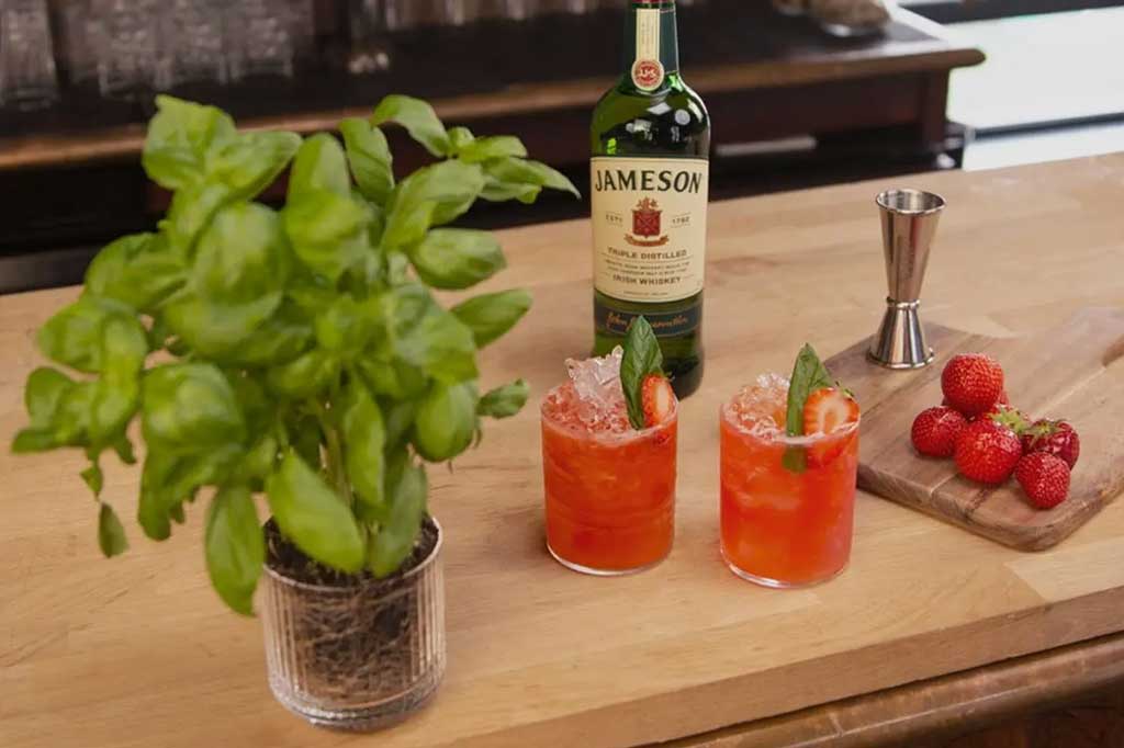 Two strawberry cocktails beside Jameson whiskey bottle