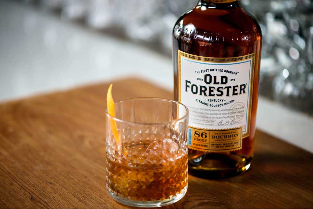 Whisky cocktail in rocks glass beside Old Forester 86 proof bourbon bottle