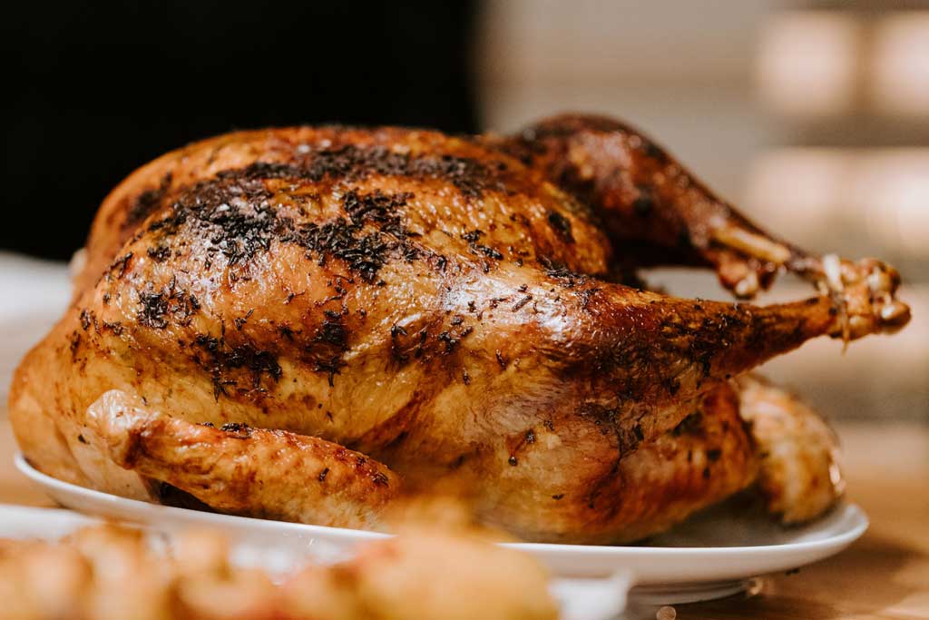 Close view of whole roasted chicken on white plate