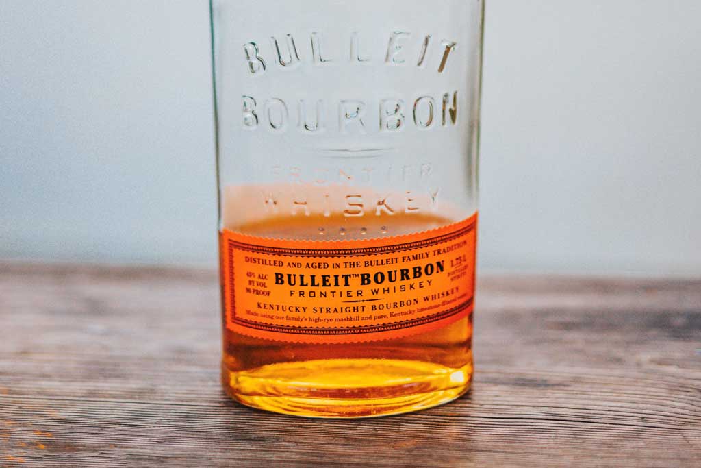 Half empty bottle of Bulleit Bourbon on wooden table