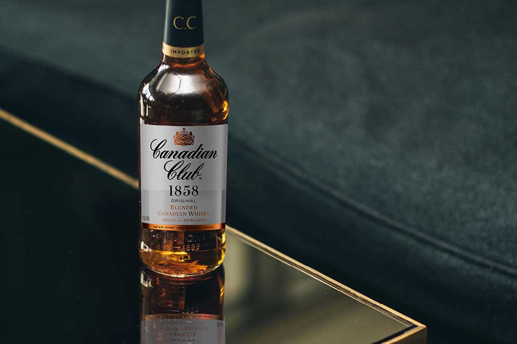 Bottle of Canadian Club whisky sitting on glass table beside sofa