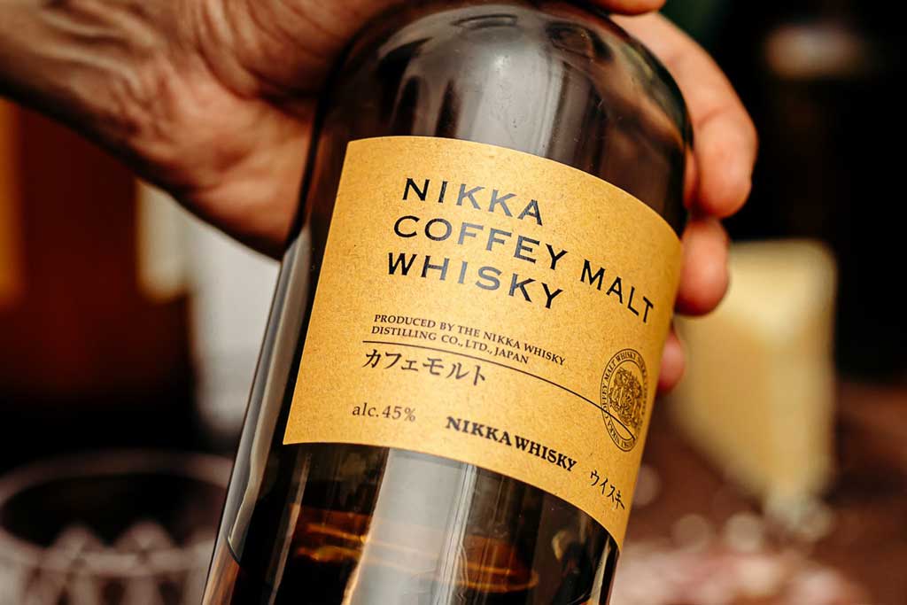 Person holding Nikka Malt whisky bottle