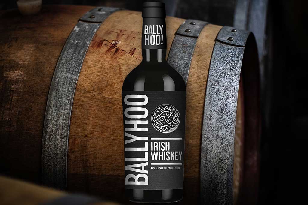 Bottle of Ballyhoo Irish Whiskey in front of wooden casks