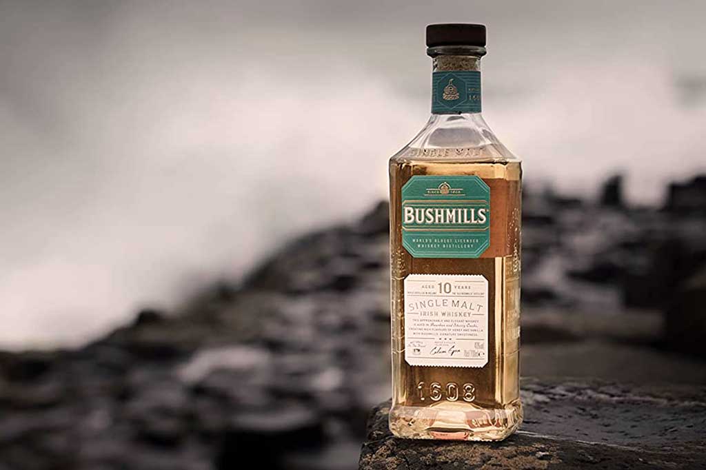 Bottle of Bushmills 10 year old Irish whiskey on rough rocks by the sea