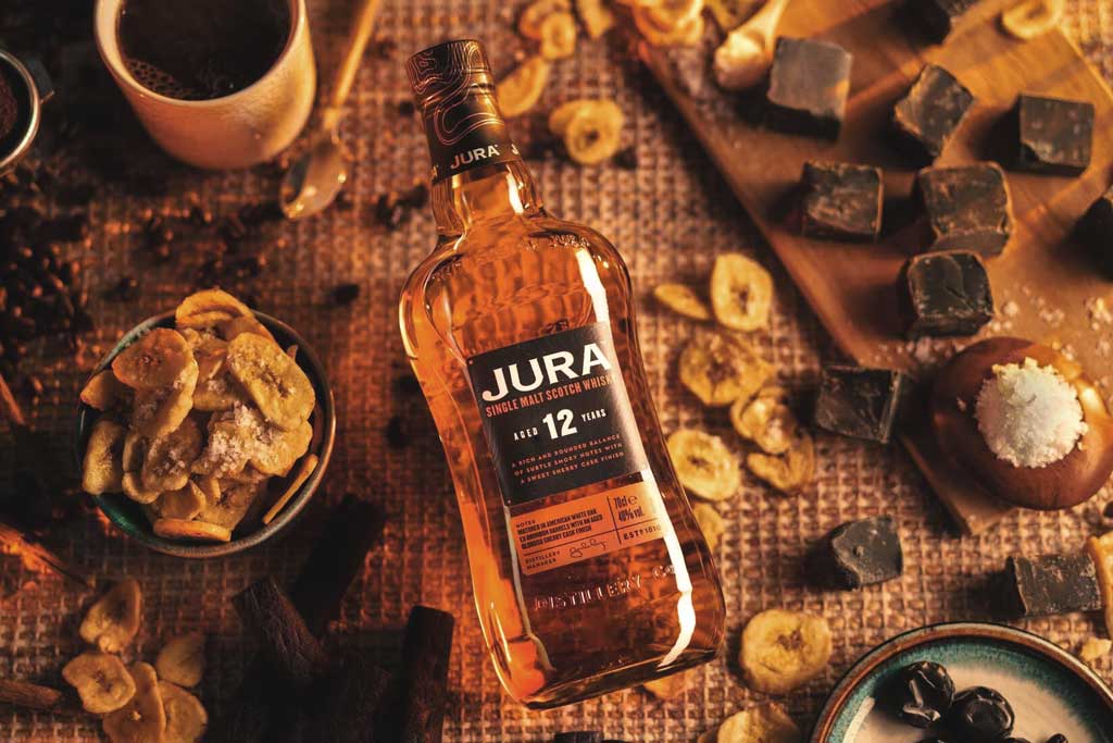 Bottle of Jura 12 Year Old Whisky lying on table beside spices and chocolate