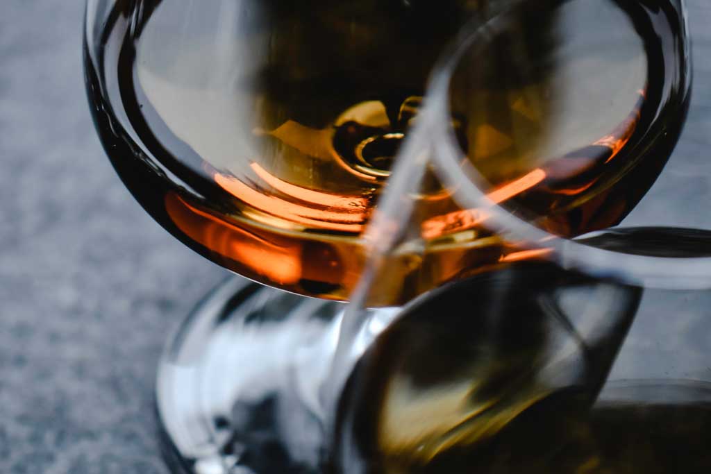 Close view of two Glencairn drinking glasses with Scotch whisky in them on dark table