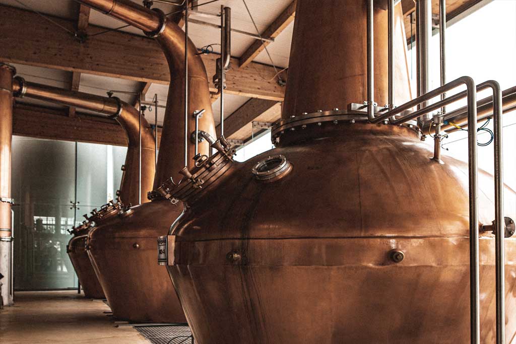 Three copper pot stills inside Irish whiskey distillery