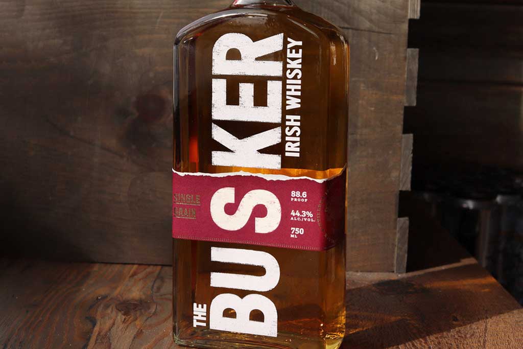 Three quarter view of Busker Single Grain Whiskey beside wooden box