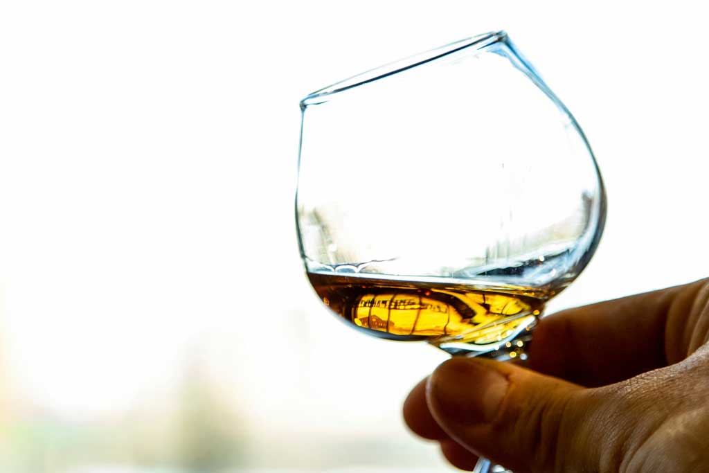 Close view of whiskey glass being held up to sunlight